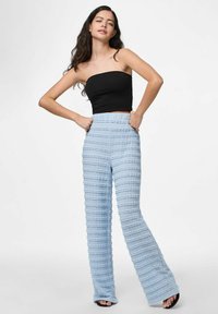 Lichtblauwe, getextureerde flared broek met een ribbelpatroon. Hoge taille, zachte stof en een losse pasvorm, gecombineerd met een zwarte strapless top.