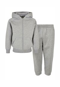 Felpa grigia in cotone con zip e tasche laterali, abbinata a pantaloni della tuta coordinati con vita elastica e caviglie affusolate.