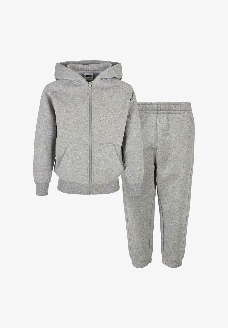 Felpa grigia in cotone con zip e tasche laterali, abbinata a pantaloni della tuta coordinati con vita elastica e caviglie affusolate.