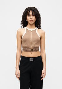 Καφέ κομμένο τοπ με λευκές πινελιές, με φερμουάρ στο μπροστινό μέρος και ζώνη με χρυσές λεπτομέρειες. Συνδυάζεται με μαύρο παντελόνι.