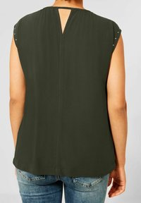 Tmavě zelený bezrukávový top s klíčovou dírou na zadní straně, hladkou texturou a malými kovovými akcenty na ramenních švech. Design v ležérním střihu.