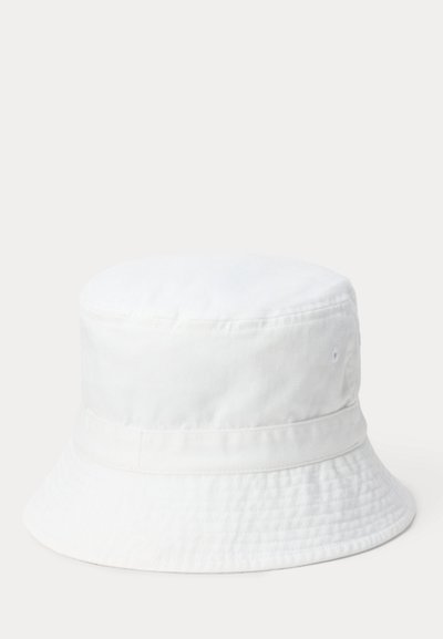 Απλό λευκό βαμβακερό καπέλο τύπου κάδος με ραμμένη φαρδιά γείσο και οπές αερισμού σε ουδέτερο φόντο.