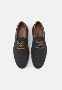 Chaussures bleu marine avec un motif en diamant texturé, lacets marron et intérieur marron. Embout arrondi et semelle plate pour un design décontracté.