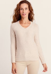 Pull en maille beige clair avec un col en V, des manches longues, un tissu texturé et de subtils éclats de couleur. Détails de bord-côte en bas et aux poignets.