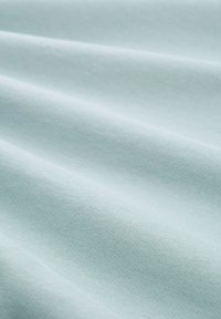 Világoskék pamut szövet sima textúrával, ami finom redőket és egységes szövésmintát mutat. Puha, könnyed megjelenés.