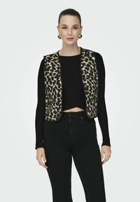 Prsluk s leopard uzorkom s crnim detaljima, preko crnog rebrastog kratkog topa, u kombinaciji s crnim trapericama visokog struka. Vidljive zlatne kružne naušnice.