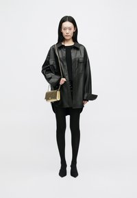 Μαύρο δερμάτινο υπερμεγέθες σακάκι, συνδυασμένο με εφαρμοστό μαύρο μπλουζάκι και κολάν. Τσάντα ώμου με χρυσή αλυσίδα προσθέτει στην κομψότητα. Μαύρα πισωτό παπούτσια.