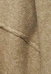 Beiges Wollgewebe mit einer weichen Textur und sichtbarem Webmuster. Das Material wirkt leicht flauschig und hat ein nahtloses Design.