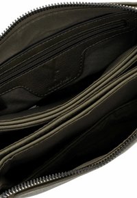 Interno di un portafoglio in pelle verde con più slot per carte, un comparto con zip e una fodera in tessuto texturizzato. Chiusura con zip nella parte superiore.