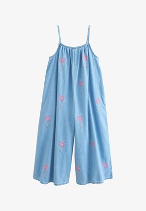 Svetlomodrá džínovina s ružovo vyšívanými palmami, zobrazuje ruku osoby odpočívajúcu v bočnom vrecku.