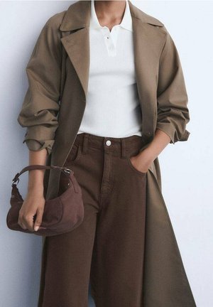 Manteau trench marron avec manches retroussées, polo blanc côtelé, pantalon large marron foncé, et un petit sac à main marron avec une anse courbée.