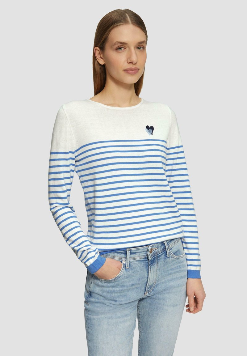 Pull rayé blanc et bleu, avec des manches longues, un col rond et un patch en forme de cœur sur la poitrine. Tissu en tricot doux et léger.