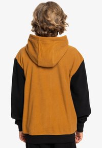 Fleece hoodie met een bruine body en zwarte mouwen, voorzien van een grote capuchon en een ontspannen pasvorm. Zachte textuur en minimalistisch ontwerp.