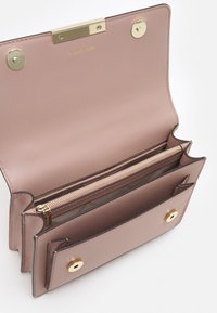 Portafoglio in pelle rosa con chiusura dorata, tasca interna con zip e due scomparti con bottone. Presenta un design minimalista e una texture liscia.