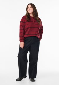 Bordeaux langetermijn polo shirt met zwarte strepen, met een drie-knopen placket. Draag het met donkere wijd-pijpen spijkerbroek en zwarte schoenen.