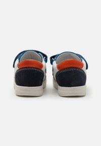 Baskets blanches avec des accents bleus et oranges. Comprend des matériaux en daim, des bandes Velcro et une semelle en caoutchouc. Vue arrière affichée.
