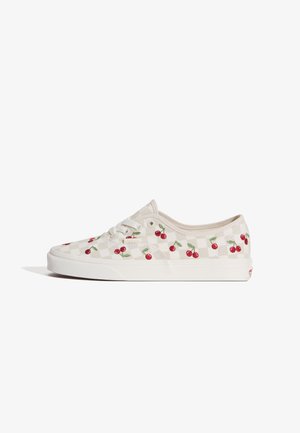 Niski biały sneaker z lekkim wzorem w kratkę oraz haftowanymi czerwonymi wiśniami z zielonymi liśćmi po bokach i białą gumową podeszwą.