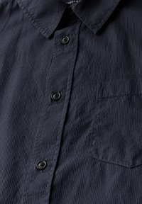 Camisa de botones azul marino de tela texturada, con cuello puntiagudo, bolsillo frontal y botones negros a lo largo de la tapeta.