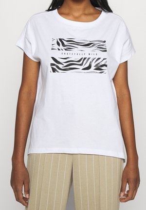 Camiseta de algodón blanca con mangas cortas que presenta un gráfico de estampado de cebra en negro y gris con el texto "GRATEFULLY WILD" debajo.