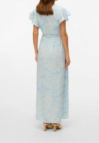 Abito lungo light blue con motivo floreale, maniche a volant corte, vita aderente e gonna fluida, abbinato a scarpe con tacco a blocco color crema.