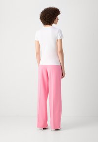 White, short-sleeve shirt paired with high-waisted, wide-leg pink trousers. Smooth texture with a simple design.