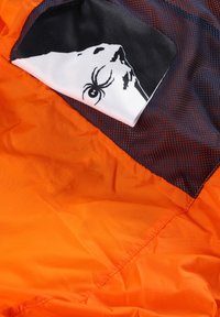 Oranges Stoff mit einer glatten Textur, der ein schwarzes Netzpanel und eine Grafik eines Gesichts auf einem weißen Tuch zeigt, das sich oben befindet.