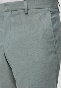 Lichtblauwe broek met een gestructureerde stof, voorzien van een voorzak, ri loops en een rechte snit. Een subtiel patroon is zichtbaar.