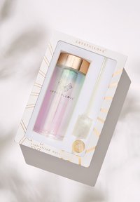 Kristallisierte Wasserflasche mit einem schimmernden Farbverlauf, goldfarbenem Verschluss und klarem Strohhalm, verpackt in einer dekorativen Box.