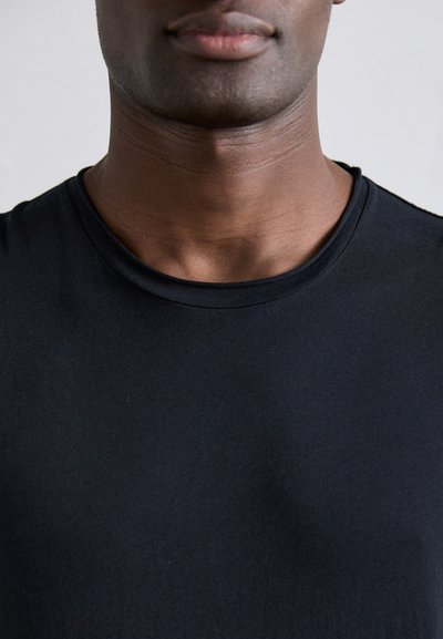 Camiseta negra de cuello redondo hecha de una tela suave y lisa. Diseño ajustado con un escote limpio y sin adornos ni patrones.