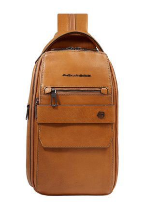 Sac bandoulière en cuir camel avec poche zippée à l'avant, poche à rabat, logo en métal noir et sangle réglable visible en haut.