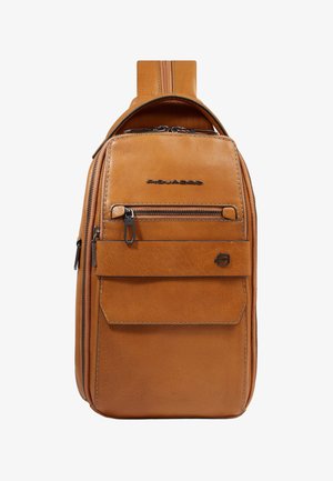 Bruine leren slingertas met voorvak met ritssluiting, klepvak, zwart metalen logo en verstelbare riem zichtbaar aan de bovenkant.