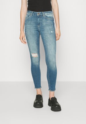 Skinny blue jeans made of denim with a distressed knee and frayed hem; features a classic five-pocket design and a brown button closure.