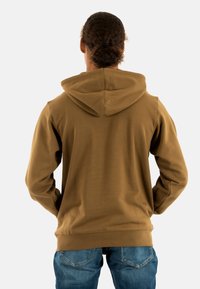 Felpa con cappuccio marrone realizzata in morbido tessuto, caratterizzata da una vestibilità rilassata, maniche lunghe e una tasca a marsupio sul davanti.