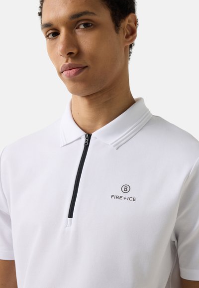 Young man wearing a white polo shirt with a black zipper and "B FIRE + ICE" logo on the left chest against a plain background.