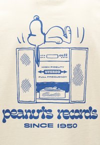 Ο Snoopy ξαπλωμένος πάνω σε ένα στερεοφωνικό σύστημα με το κείμενο «High Fidelity Stereo Πλήρες Φάσμα Συχνοτήτων» και «Peanuts Records από το 1950» από κάτω.