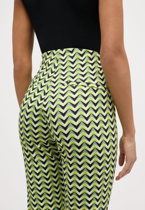 Pantalons taille haute avec un motif en zigzag vert, noir et blanc. Ils ont une coupe ajustée, des poches arrière et une texture lisse.