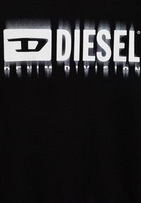 Maglietta nera con un grande logo bianco Diesel e il testo "DENIM DIVISION" sottostante. Il design include un effetto di sfumatura a gradiente.