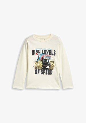 T-shirt a maniche lunghe color crema con una grafica di un camion mostro blu e rosso, dotato di pneumatici verdi sovradimensionati e testo in grassetto nero: "ALTI LIVELLI DI VELOCITÀ."