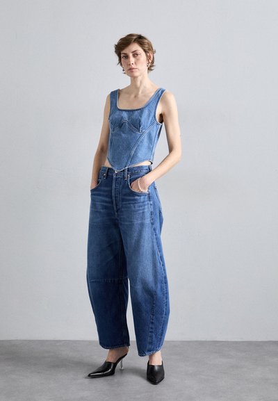 Denim korzet s kvadratnim dekolteom, uparen s labavim, visokim trapericama. Crne špicaste potpetice upotpunjuju odjevnu kombinaciju.