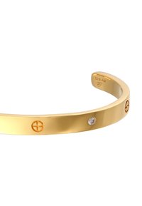 Bracciale a manica in metallo dorato con superficie liscia e lucida, caratterizzato da accenti circolari e una piccola pietra preziosa trasparente. Contrassegnato con "925 A9."
