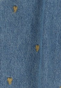 Tissu en denim bleu clair avec de petites broderies en forme de cœur beige dispersées sur la surface, doté d'un motif de tissage texturé.