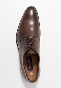 Scarpa in pelle marrone con finitura lucida, punta affilata e design con lacci. Presenta una texture liscia e una soletta con logo.