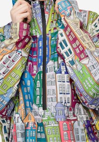 Kleurrijk jack met illustraties van huizen. Gemaakt van lichtgewicht stof met een ritssluiting, met levendige kleuren in een gevarieerd patroon.