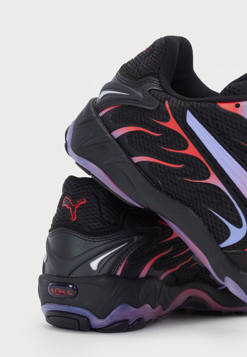 Zapatillas deportivas de malla negra con patrones de llamas rojas y moradas, que cuentan con una suela texturizada y acentos de logo distintivos en el talón.