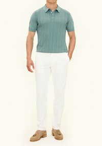 Mintgroene geribbelde polo met korte mouwen, gecombineerd met witte op maat gemaakte broeken en beige loafers met kwastaccenten.