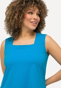 Top senza maniche in tessuto blu brillante. Presenta un collo quadrato e un aspetto liscio e strutturato. Ideale per un abbigliamento casual.