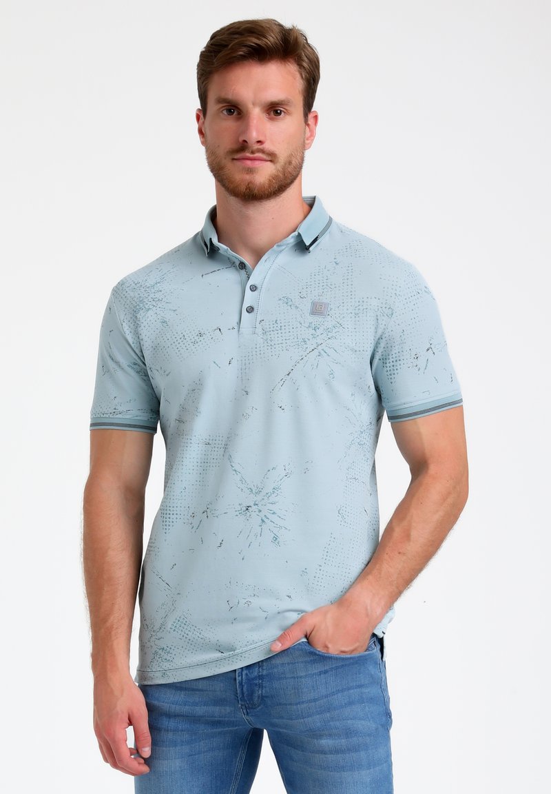 Gaiši zils polo krekls ar īsām piedurknēm, teksturēta raksta, divu pogu apkakle un kontrastējošas horizontālas svītras apkaklē un piedurknēs.