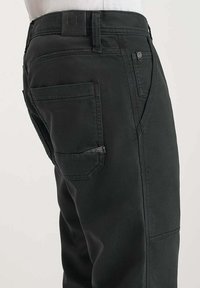 Zwarte werkbroek met versterkte stiksels, meerdere utility zakken en een leren merkpatch op de tailleband.