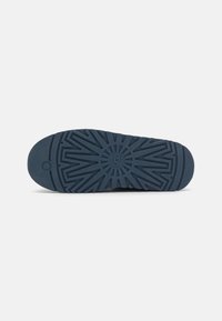 Blue rubber shoe sole with a textured, geometric pattern and a circular logo centered. Features rounded edges and a sturdy design.