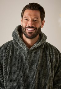 Große, charcoal-graue Kapuzenjacke aus strukturiertem Strickstoff mit einer großen Kapuze und einem lockeren Schnitt. Innenfutter aus weichem Fleece.